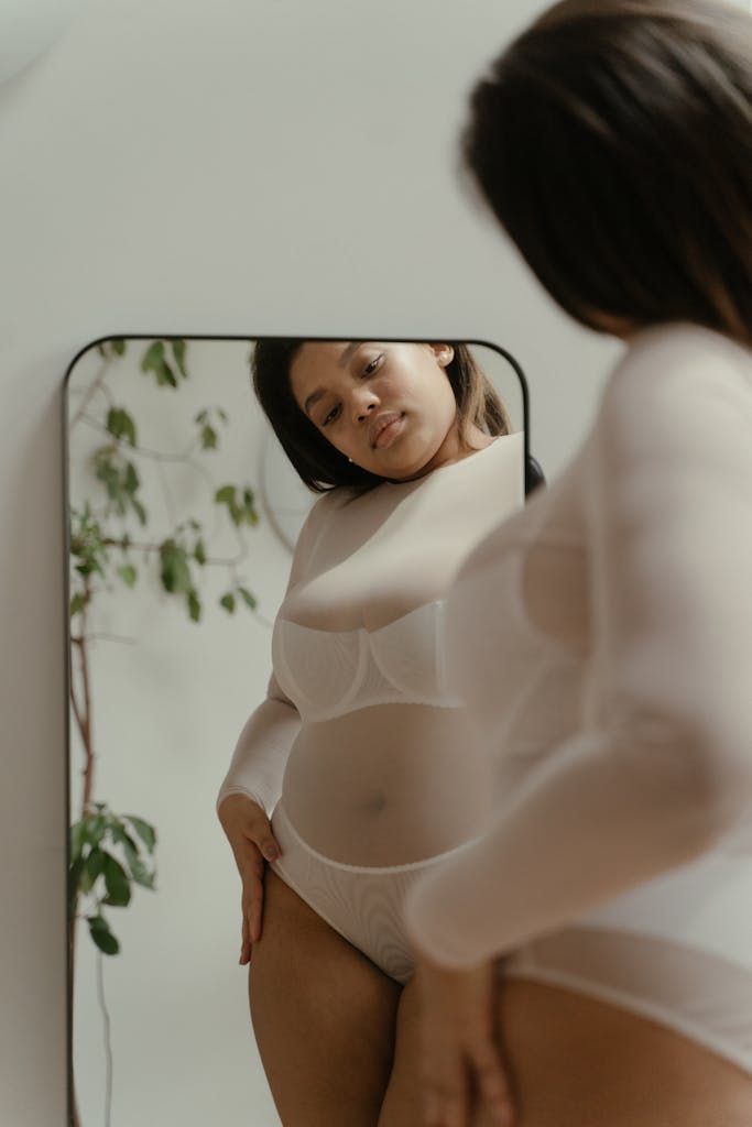 A woman embraces self-love and body positivity in a reflective mirror portrait. Self trust