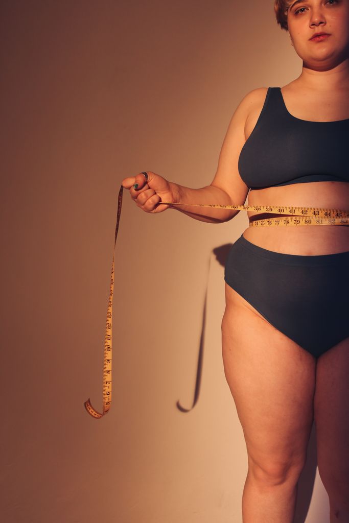 Empowering image of a plus-size woman in underwear embracing body positivity with a measuring tape.
plus size shopping tips